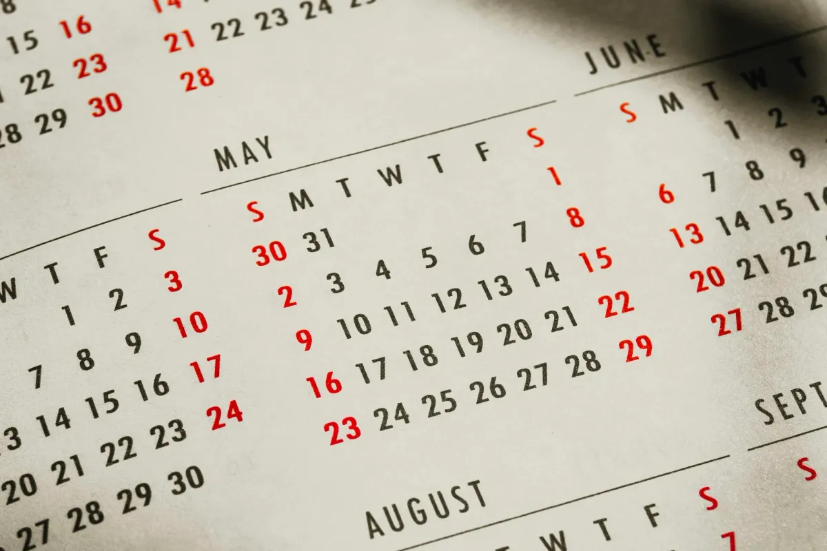 Ein gedruckter Jahreskalender in Nahaufnahme, schräg fotografiert: Mai in der Mitte, daneben Juni und August, die Sonntage in Rot, ein Schatten fällt von rechts oben über das Blatt
