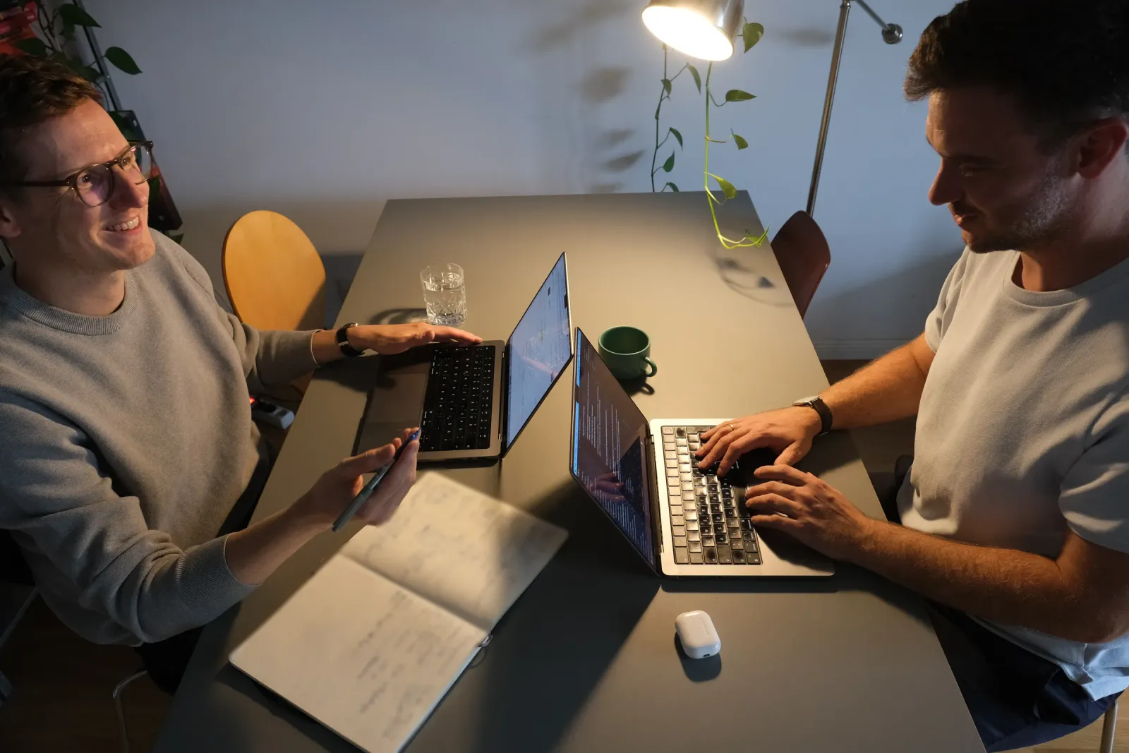 Jan Hoppe und Philipp Kaiser an einem Tisch mit zwei Laptops und einem aufgeschlagenen Notizbuch, im Gespräch